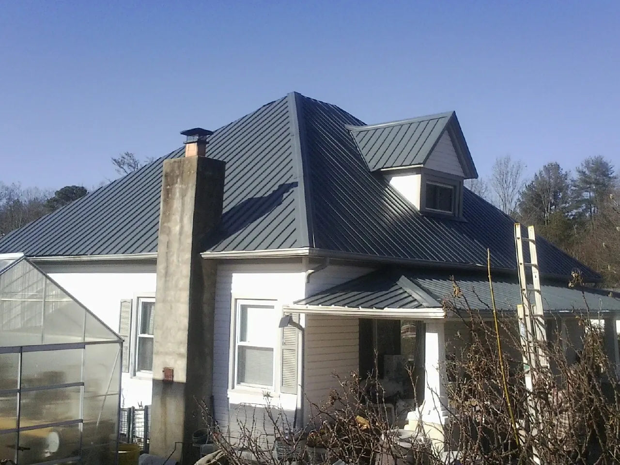 Dark blue standing seam metal roof on a white farmhouse with dormer — Slate & Tile Roof Repair by Roofing Brothers in Middlesboro