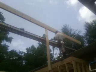 Carpenter setting a ridge beam over a new addition frame — Ice Dam Removal by Roofing Brothers in Middlesboro