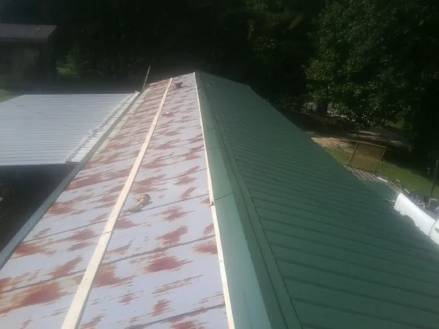 Old rusted panels beside newly installed green metal roofing — Wind Damage Roof Repair by Roofing Brothers in Middlesboro