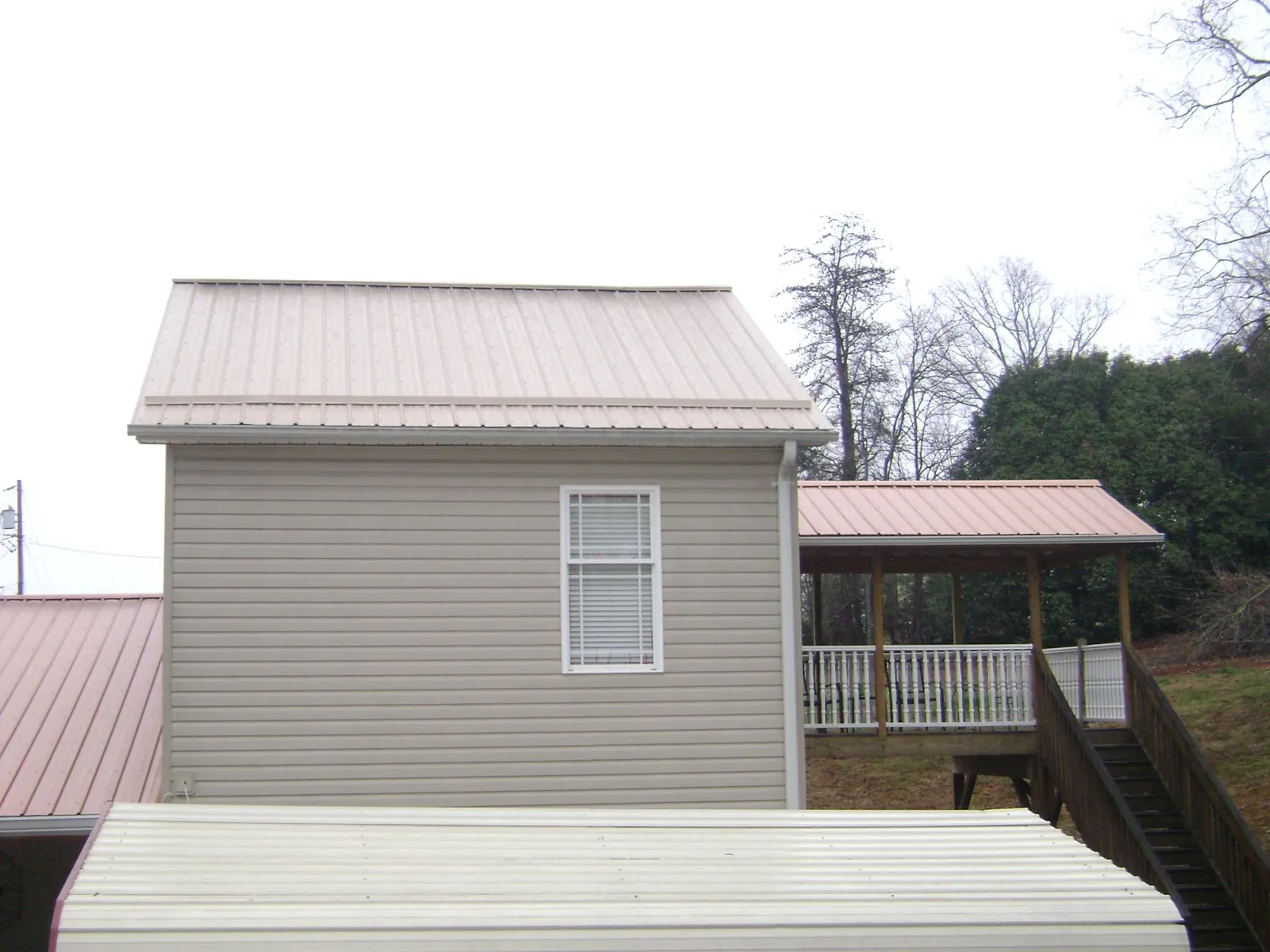 Tan metal roofs on a two story addition and attached porch, from a Roof Replacement job in Middlesboro
